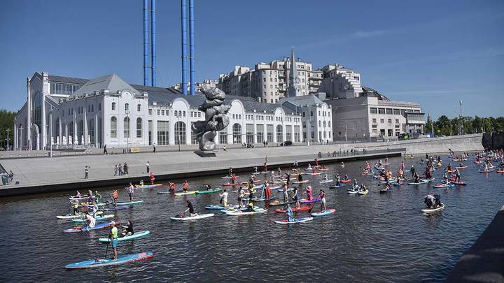 Карнавальная сап-регата проплывает на фоне «ГЭС-2» — одной из старейших электростанций Москвы, которую вывели из эксплуатации, отреставрировали и превратили в современный культурный центр. Регата прошла в рамках фестиваля «Рыбная неделя» в составе большого фестиваля «Лето в Москве» / Фото: Наталья Феоктистова / Вечерняя Москва